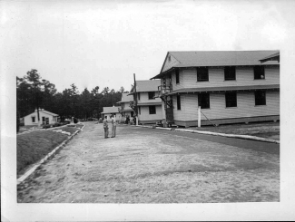 "A picture of most of our company street. The Orderly Room is on the left. The buildings on the right are barracks."